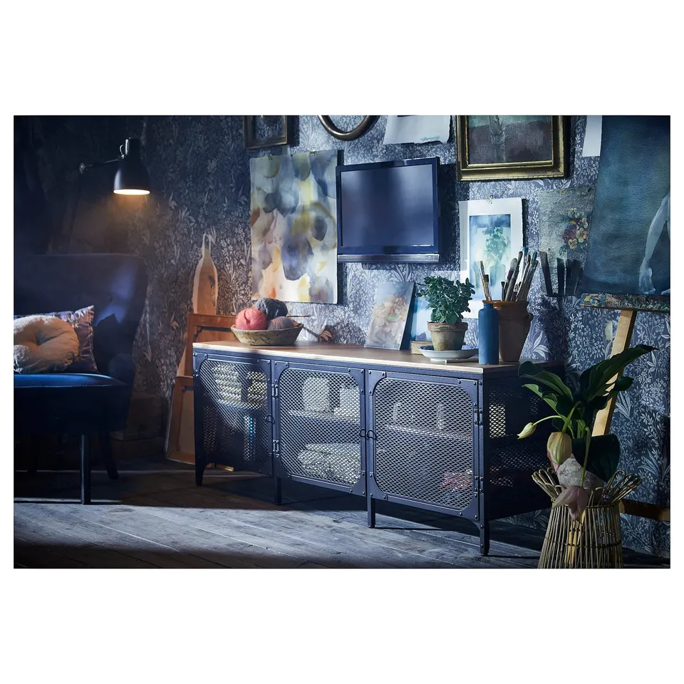 Cosy living area with blue and wooden tv stand, chair, wall art, and plants.