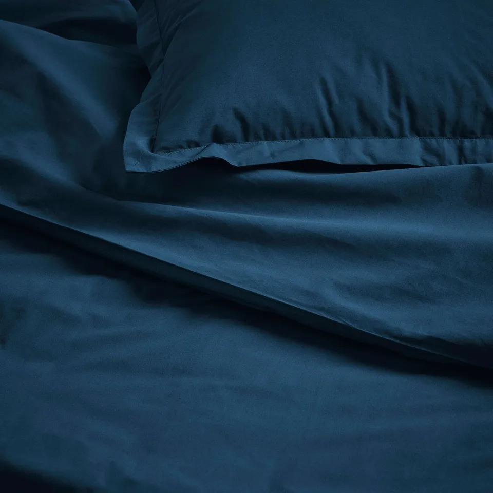 Dark blue bedding set with crisp, smooth fabric, featuring pillowcases and duvet, made of soft cotton.