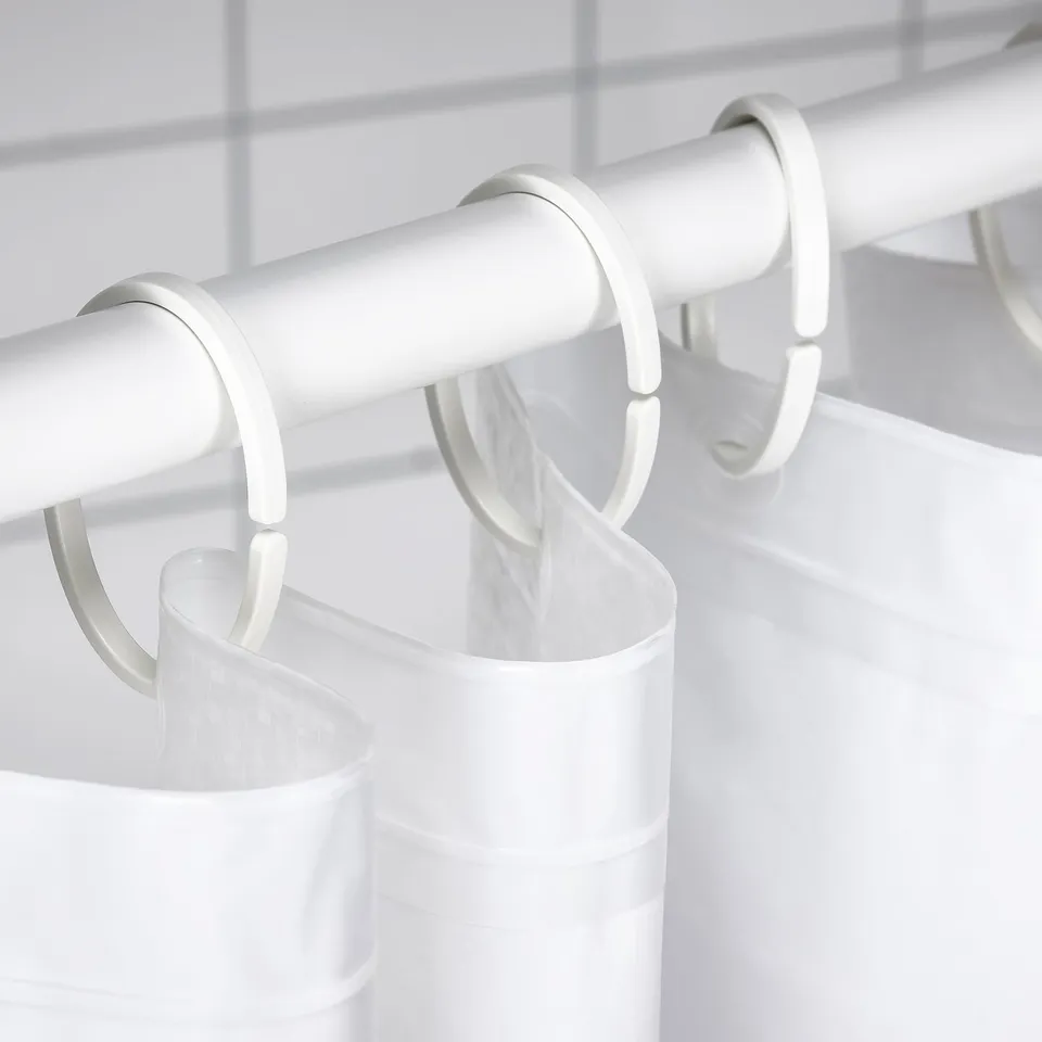 White shower curtain rod with hooks holding an opaque, waterproof curtain for privacy.