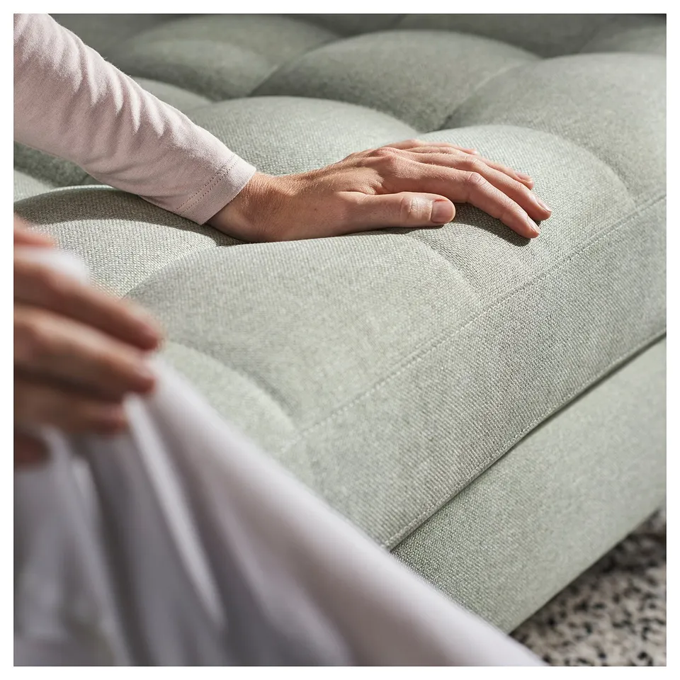 Person testing a green LANDSKRONA sofas cushion, ensuring comfort.