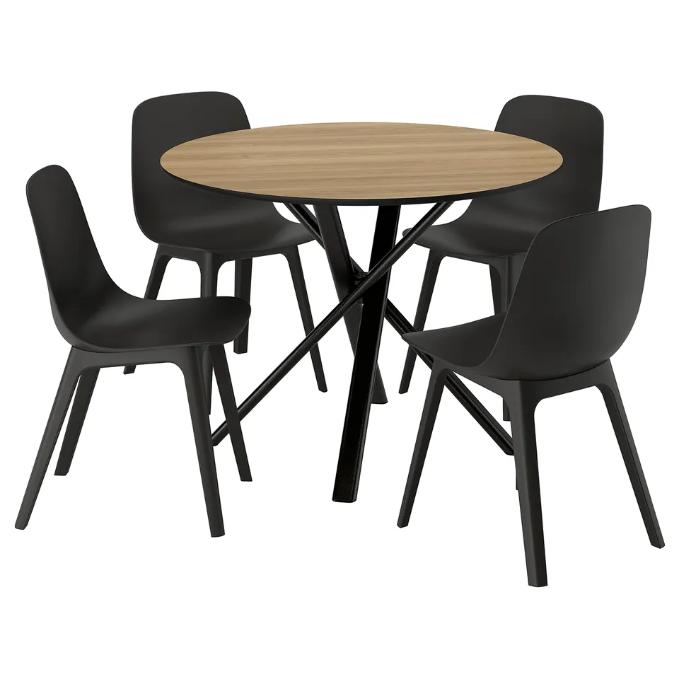 A modern dining set with a black round table and four matching black chairs. The table has a light wooden top and sleek metal legs.