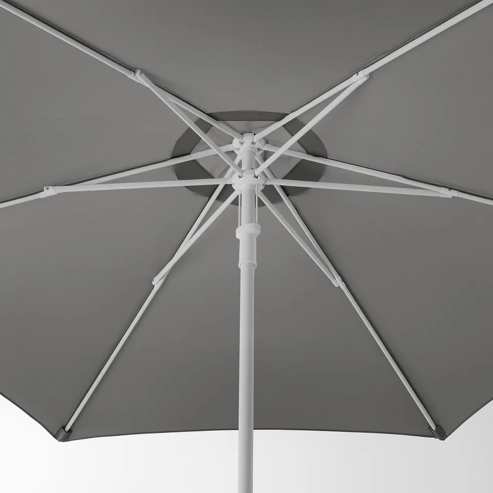 Grey patio umbrella with white ribs, open and upright against a plain sky, showcasing quality materials and sturdy construction.