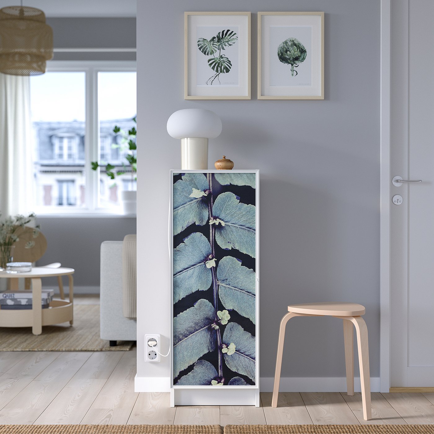 Modern room with HÖGBO glass door, blue floral pattern. Wooden stool, plant pictures, white lamp, and outdoor view.