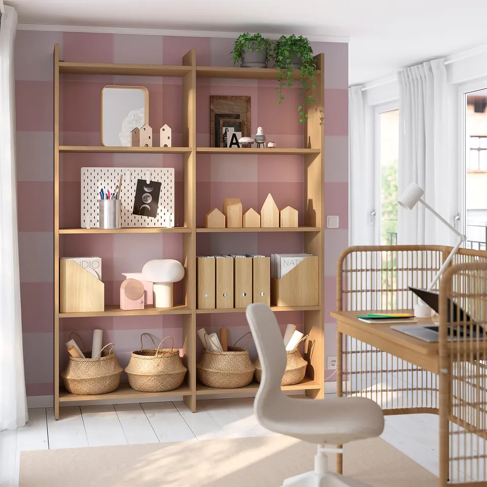 Home office: LÅDMAKARE light wood shelves against purple striped wall, holding books, baskets, decor. White desk, chair, and lamp nearby.