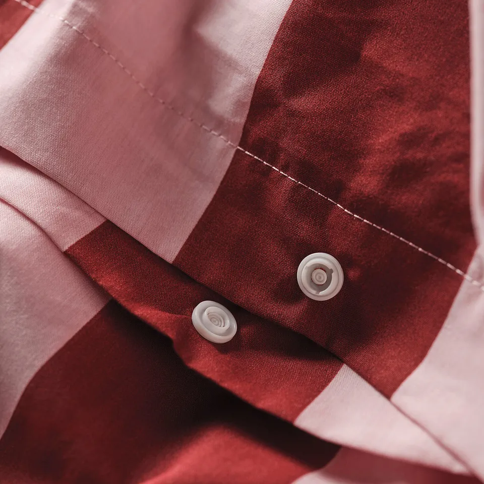 A close-up view of a duvet cover set with red and white stripes and two white buttons.