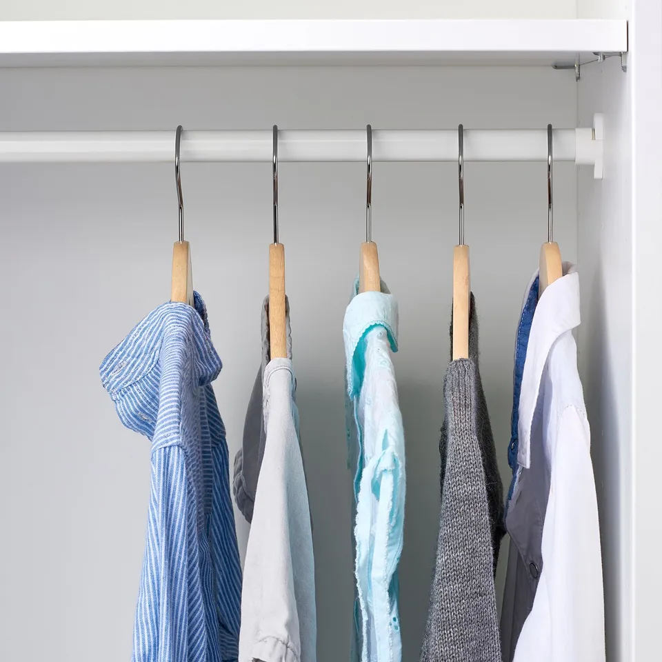 Hanging children's clothes on wooden hangers in closet.