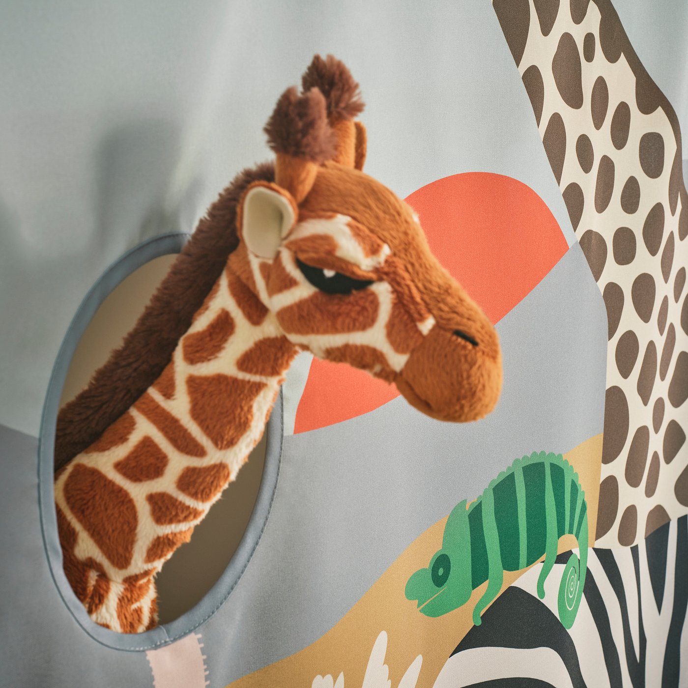 Giraffe toy peeps through soft, detailed curtain with vibrant, recycled fabric, attached securely.