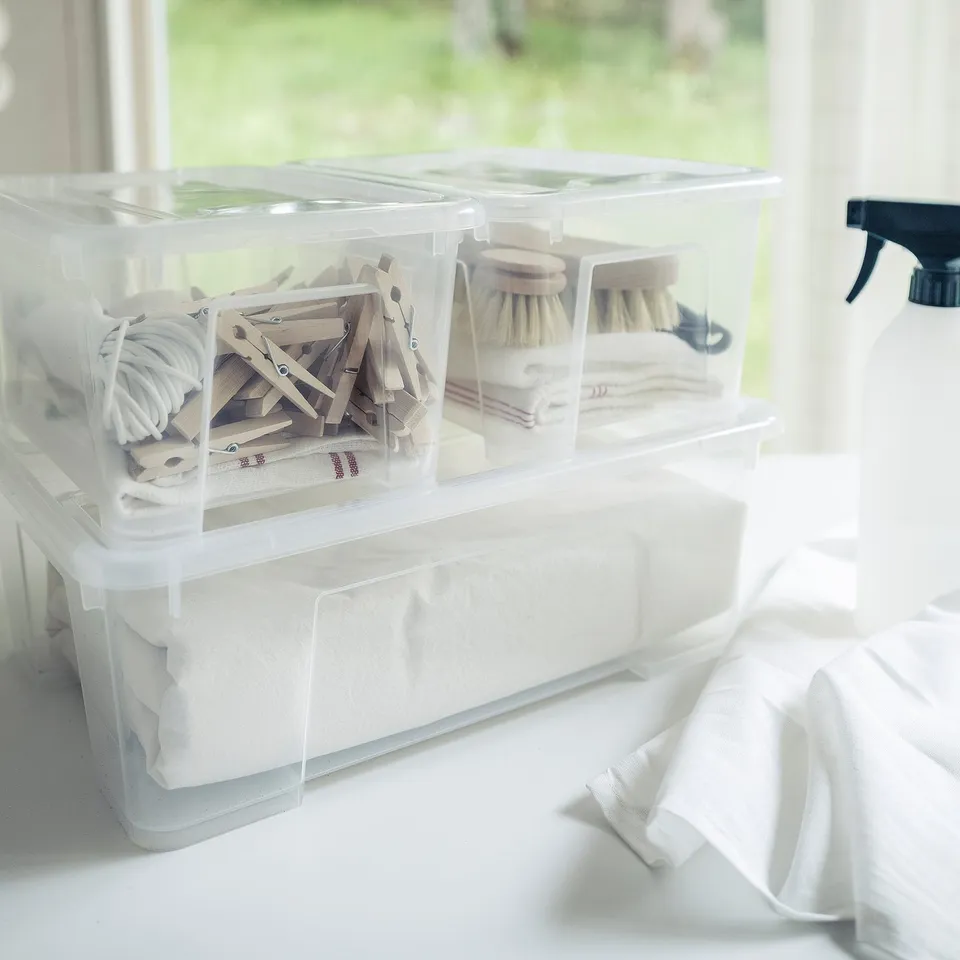 Transparent storage boxes hold clothes pegs, brushes, and tissues. Stackable, ideal for organising small items near a window.