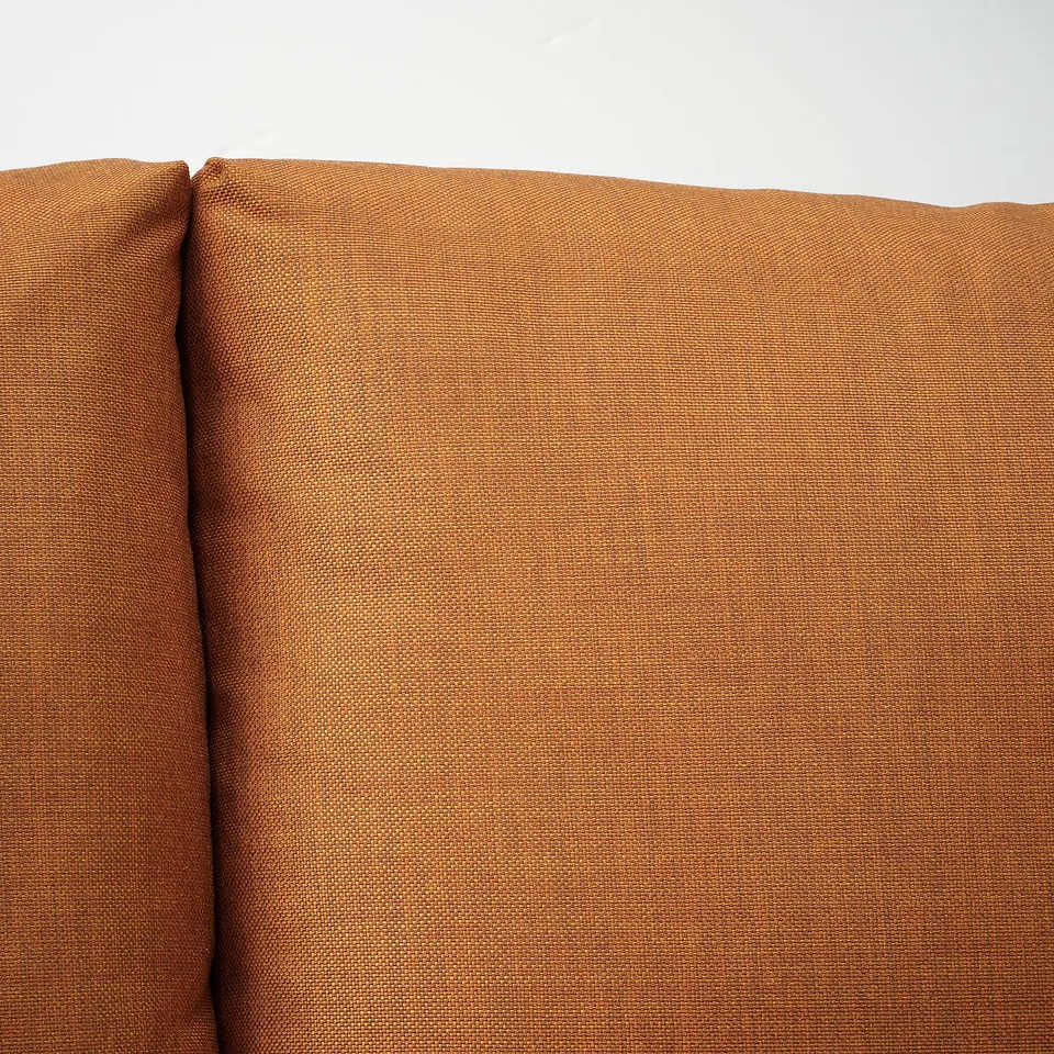 Close-up of FRIHETEN sofas textured, orange-brown fabric, showcasing its quality and comfort.