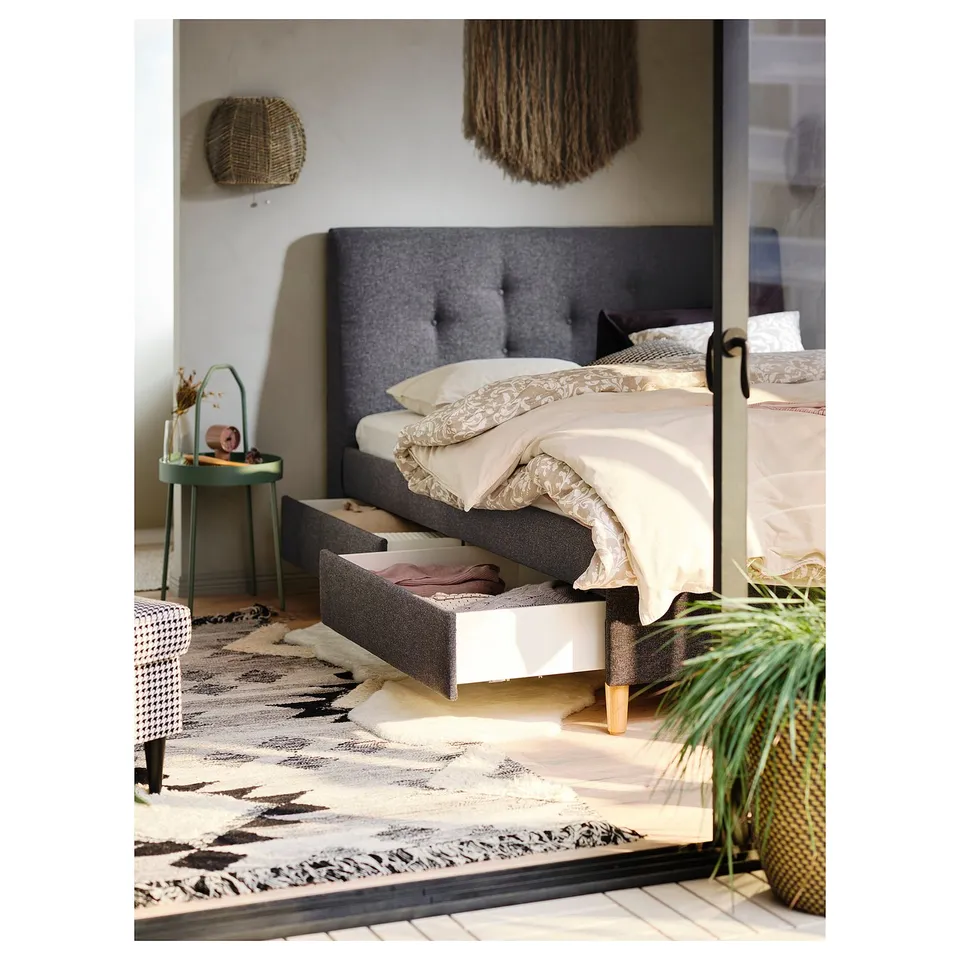 Cosy bedroom with grey bed, white linens, green side table, large rug.