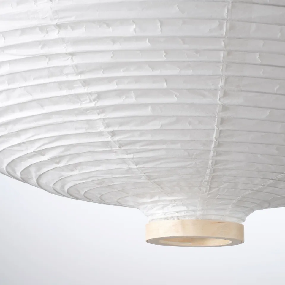 Modern pendant lamp featuring a layered rice paper shade. Has a wooden base and emits soft, diffused light.