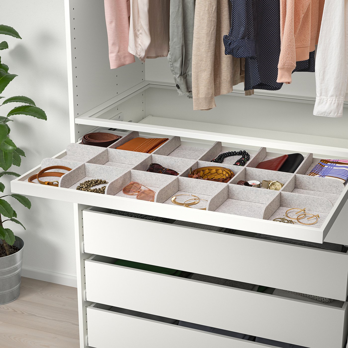 A white wardrobe organiser tray with 18 compartments, holding belts, bracelets, and wallets, pulled out for easy access.
