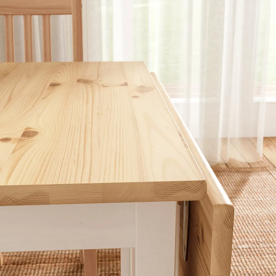 Light wooden table, smooth surface, clean lines, and natural grain texture. Bright and sturdy, set against a window with sheer curtains.