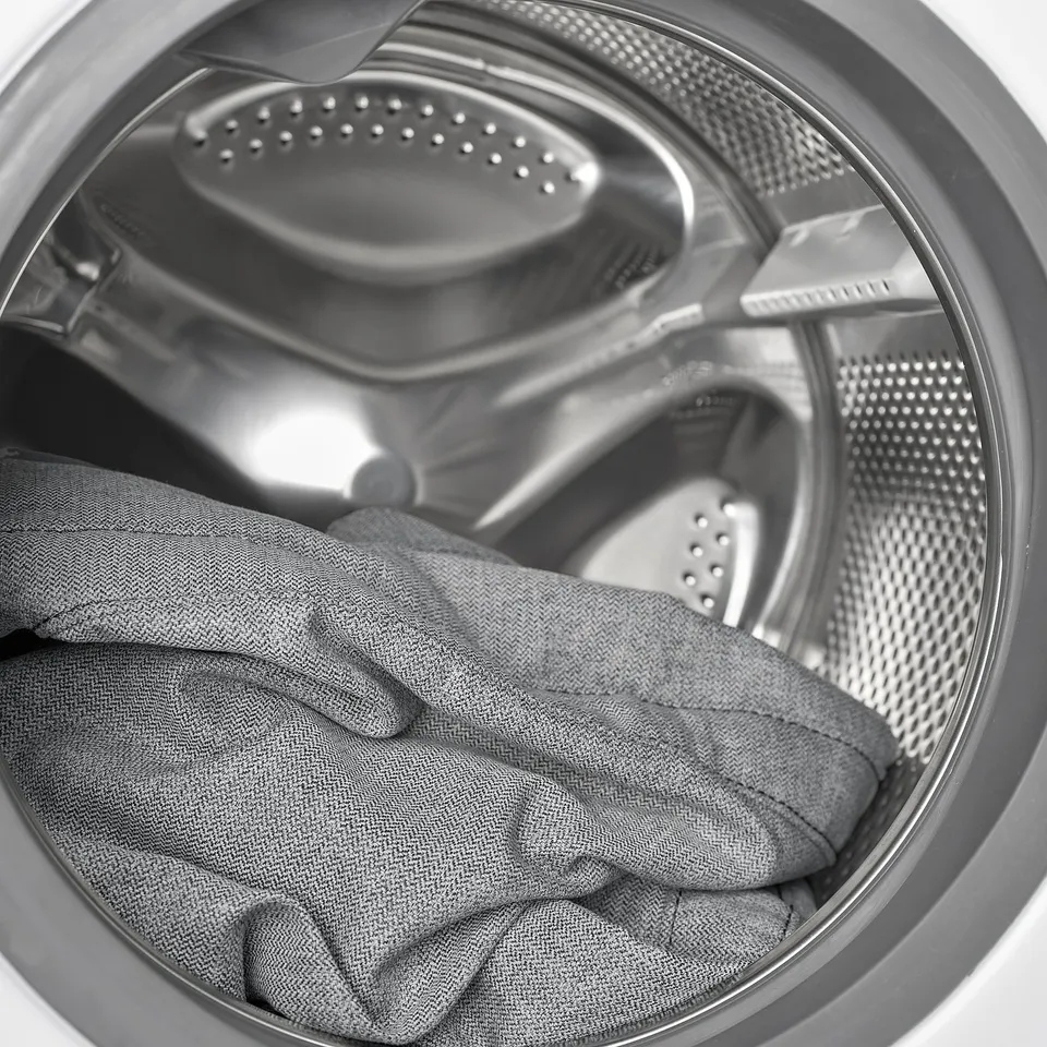 Washing machine drum with grey fabric inside, showing removable, machine-washable cover.