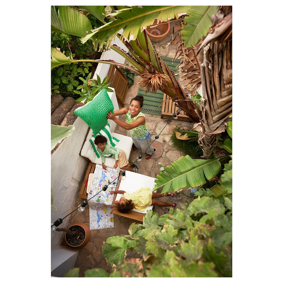 Three kids playing outdoors with plants; one holds a chair, another by map.