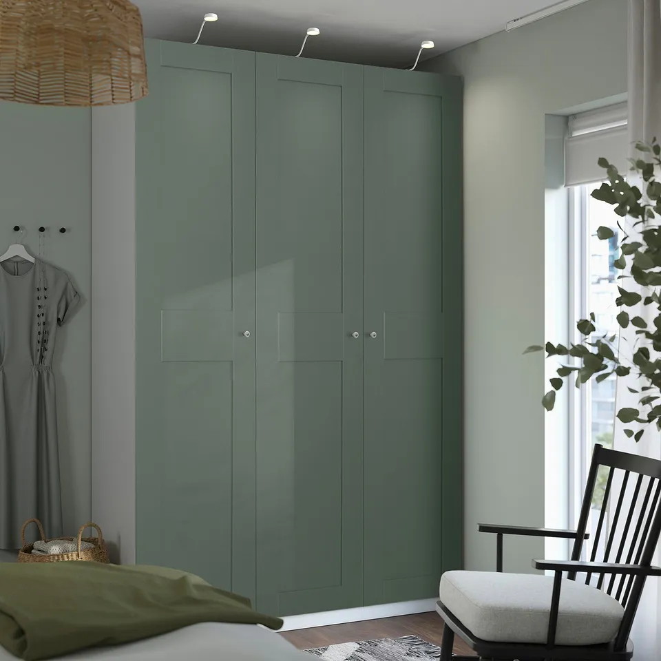 Modern bedroom with green PAX wardrobe, lighting, grey dress, window blinds, calm decor.