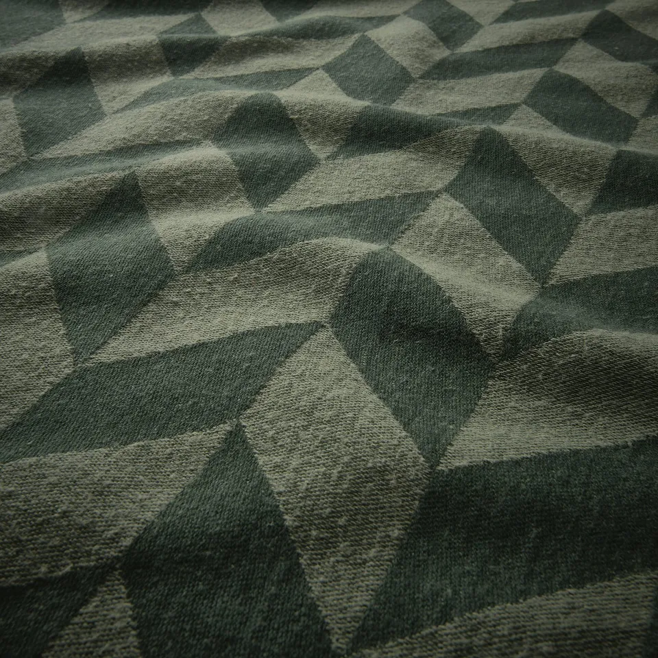 Texture of geometric patterned kitchen towel in shades of green, showcasing high-quality weave and material.