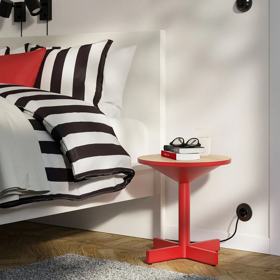 Red grimstabo side table with books between bed & wall.