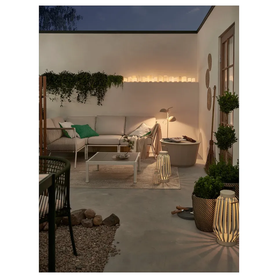 Modern patio with beige seating, plants, and lanterns, creating a cosy ambiance.