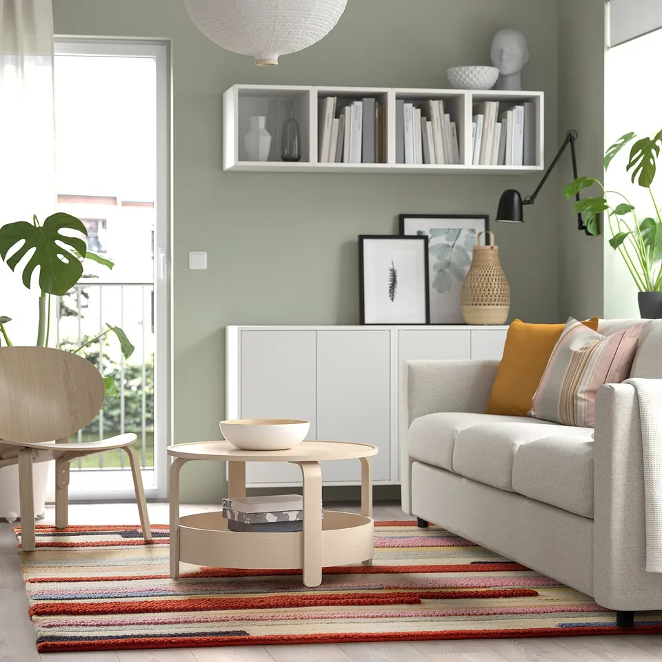 Modern living room with multicolor handwoven rug under grey sofa & plants.