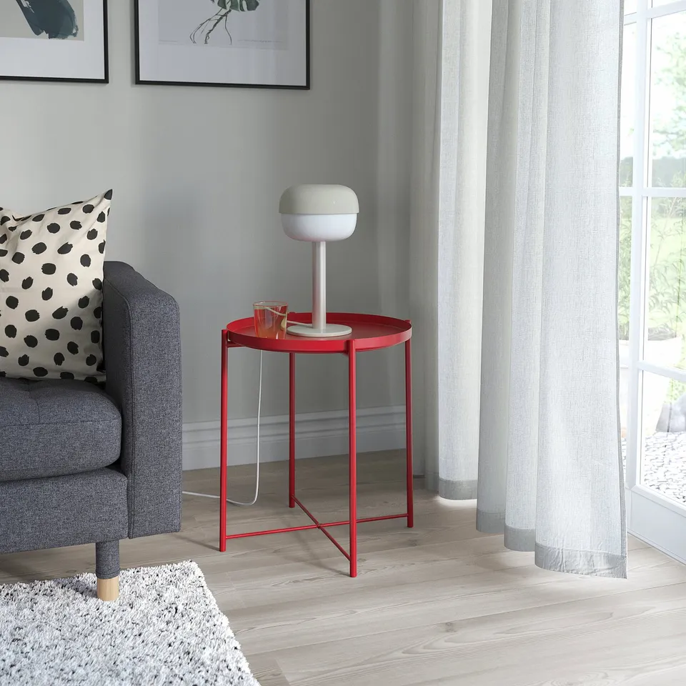 Modern living room with red BLÅSVERK lamp beside grey armchair near window.