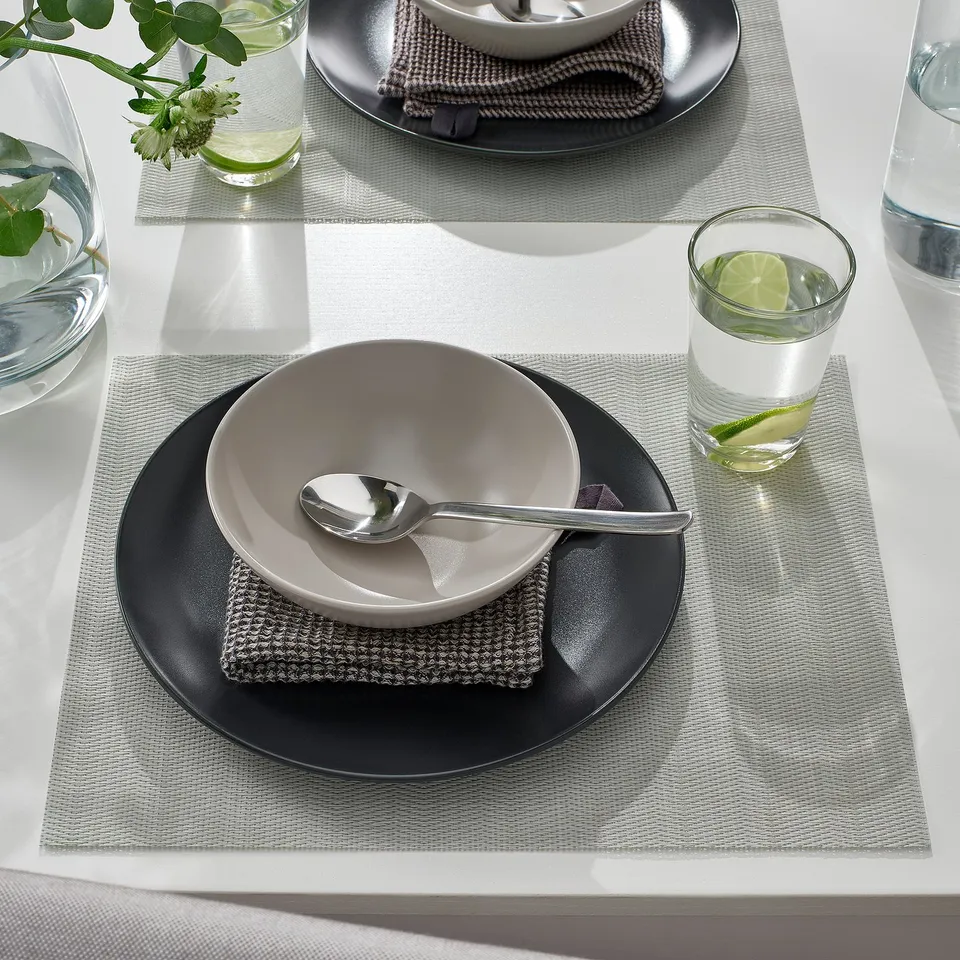 Table setting with FLYGFISK place mats, bowl, spoon, and drink with lime.
