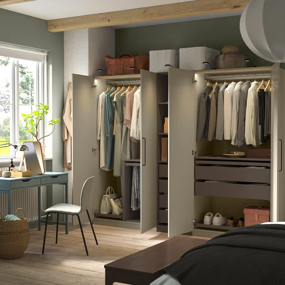 Modern bedroom with open wardrobe showcasing clothes, drawers, and shelves, part of the PAX system.