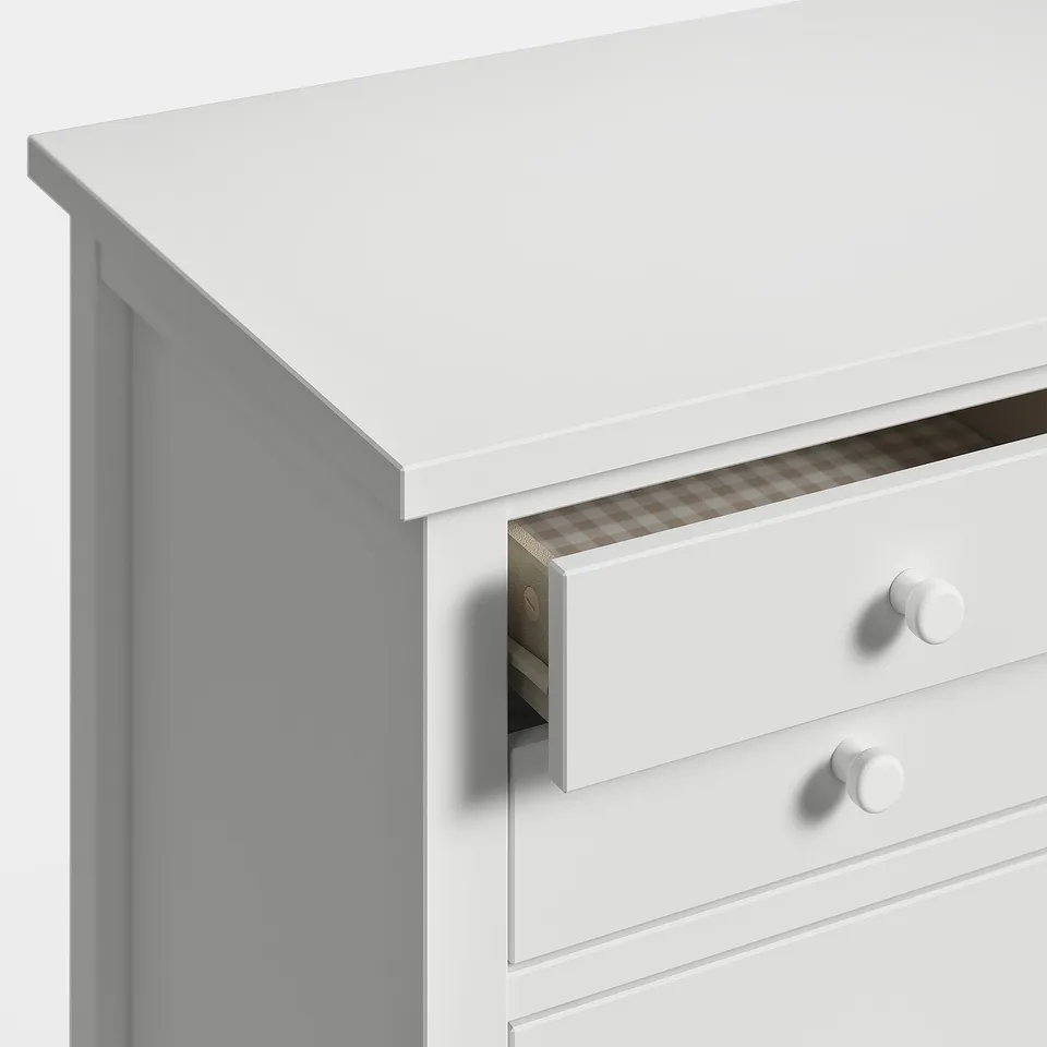 White wooden chest, narrow top, rounded knobs, one open drawer.