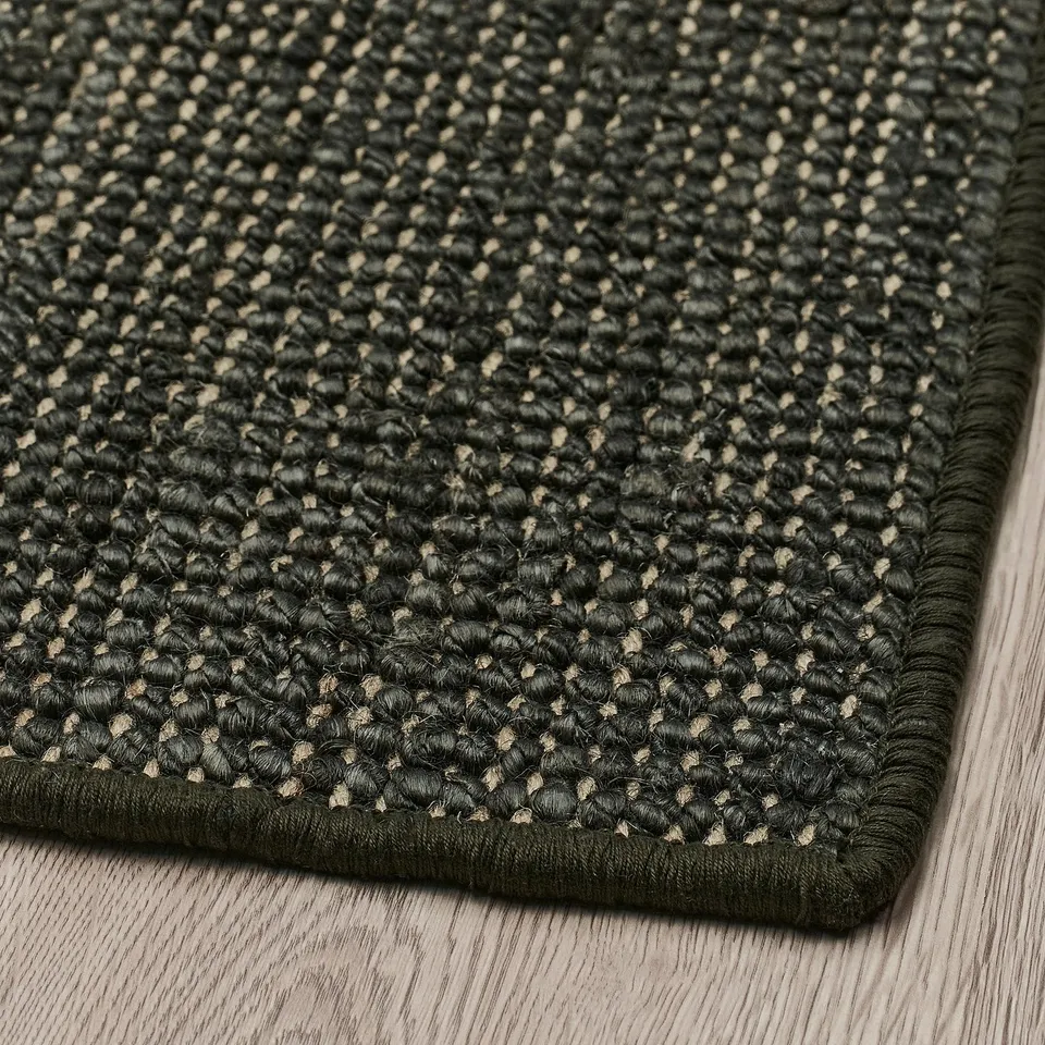 Dark green textured jute door mat on wooden floor. Thick, durable with latex backing, looks high-quality.