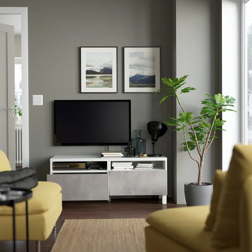 Modern living room with grey tv stand, yellow chairs, and large tv, neatly organised.