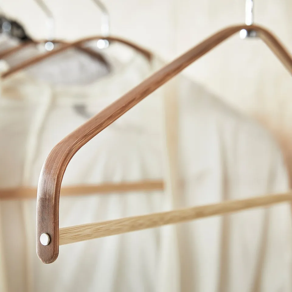 HÖSVANS bamboo hanger close-up, showing light brown wood, curved shape, metallic hook detail.