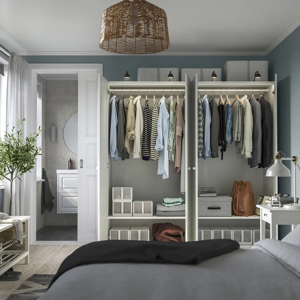 Bedroom with a PAX wardrobe displaying clothing, shelves, and drawers, including a mirror and lighting.