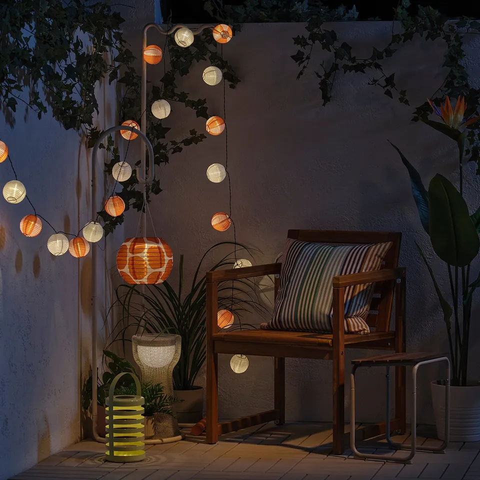 Cosy patio with string lights, wooden chair, and plants. Ideal for relaxation.
