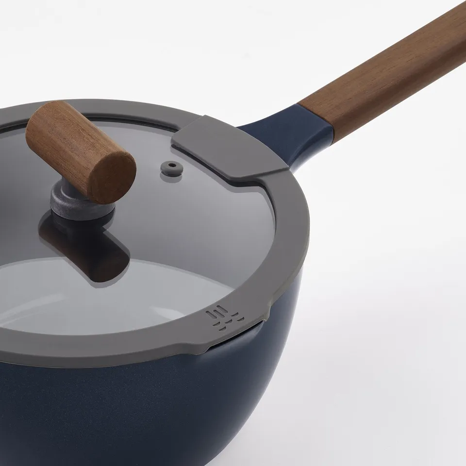 Modern saucepan with wooden handle and glass lid: close-up view
