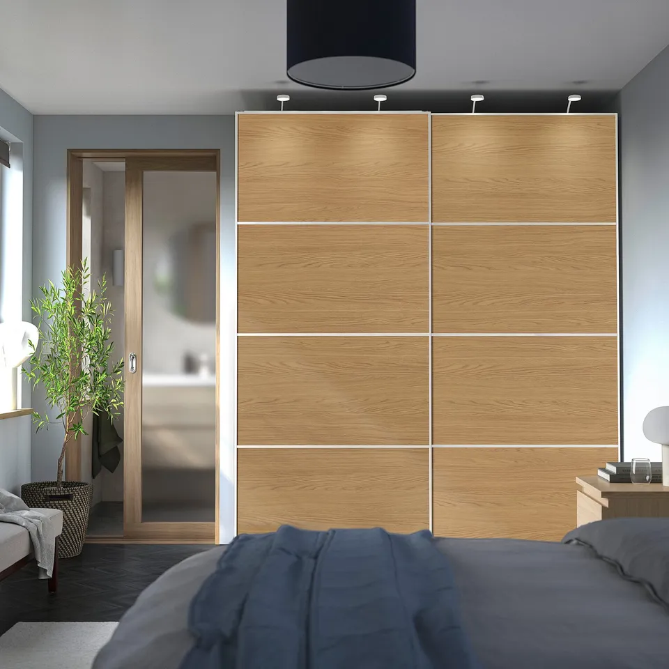 A large, modern wooden wardrobe with sliding doors, creating a warm, minimalist bedroom.