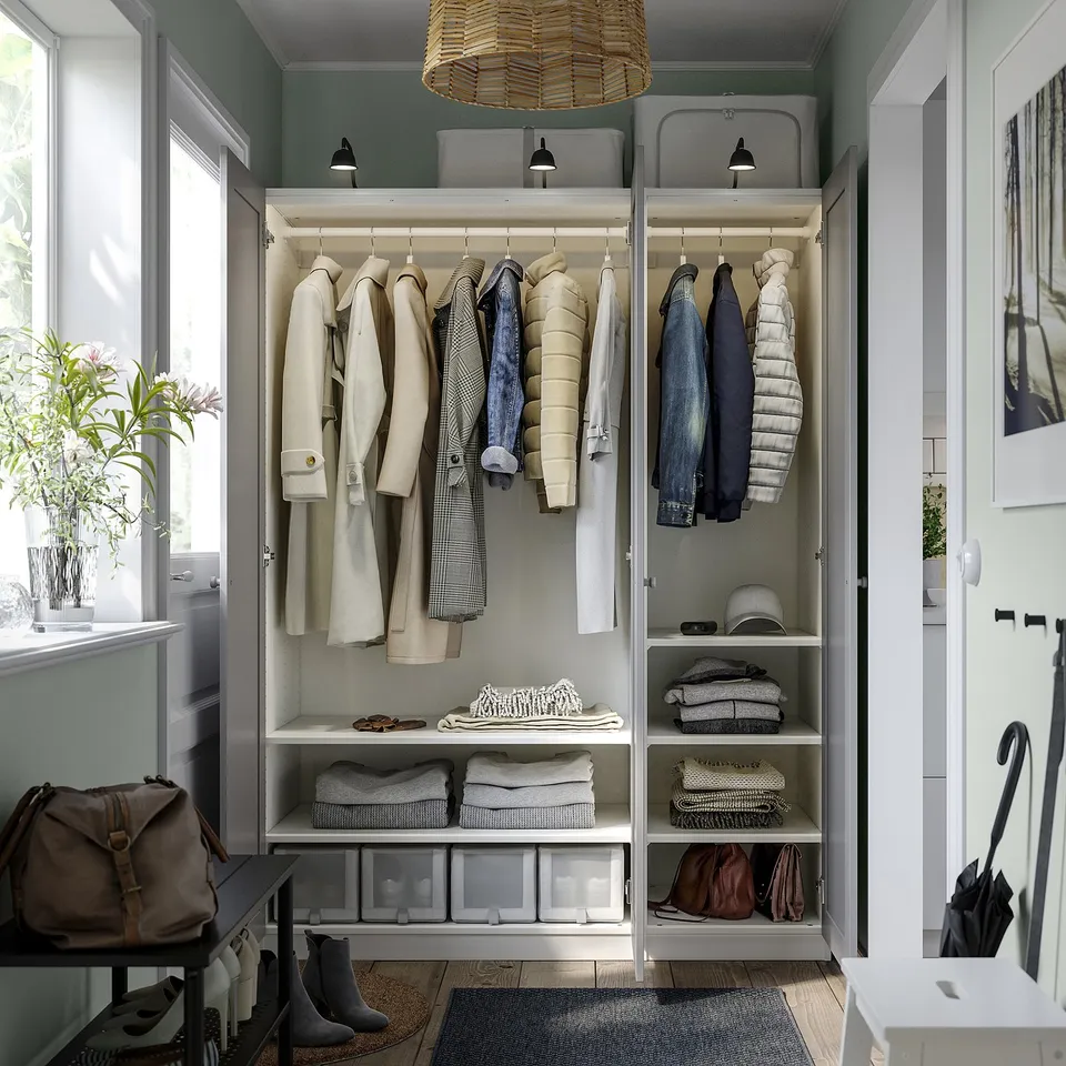 Open closet with coats, jeans, folded clothes, and storage bins, featuring integrated lighting and adjustable shelves.
