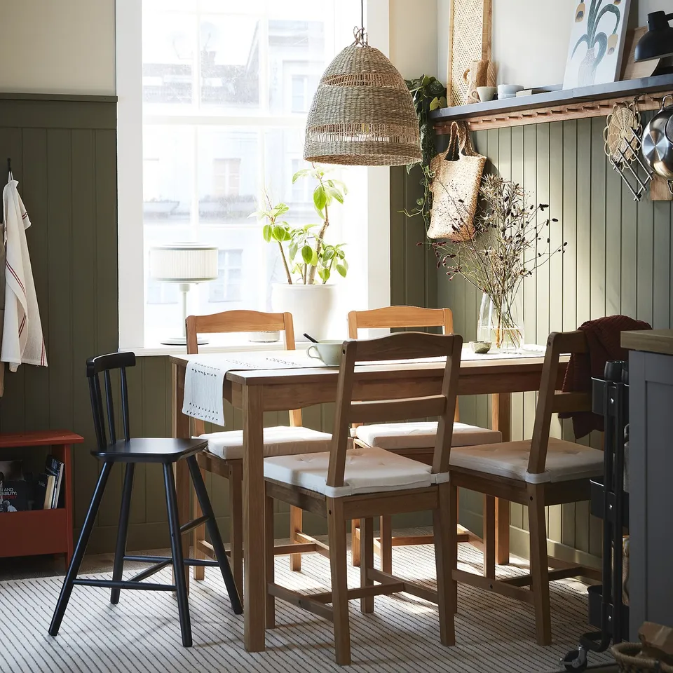 Rustic dining set with wooden table & chairs, warm room, pendant light, window view.