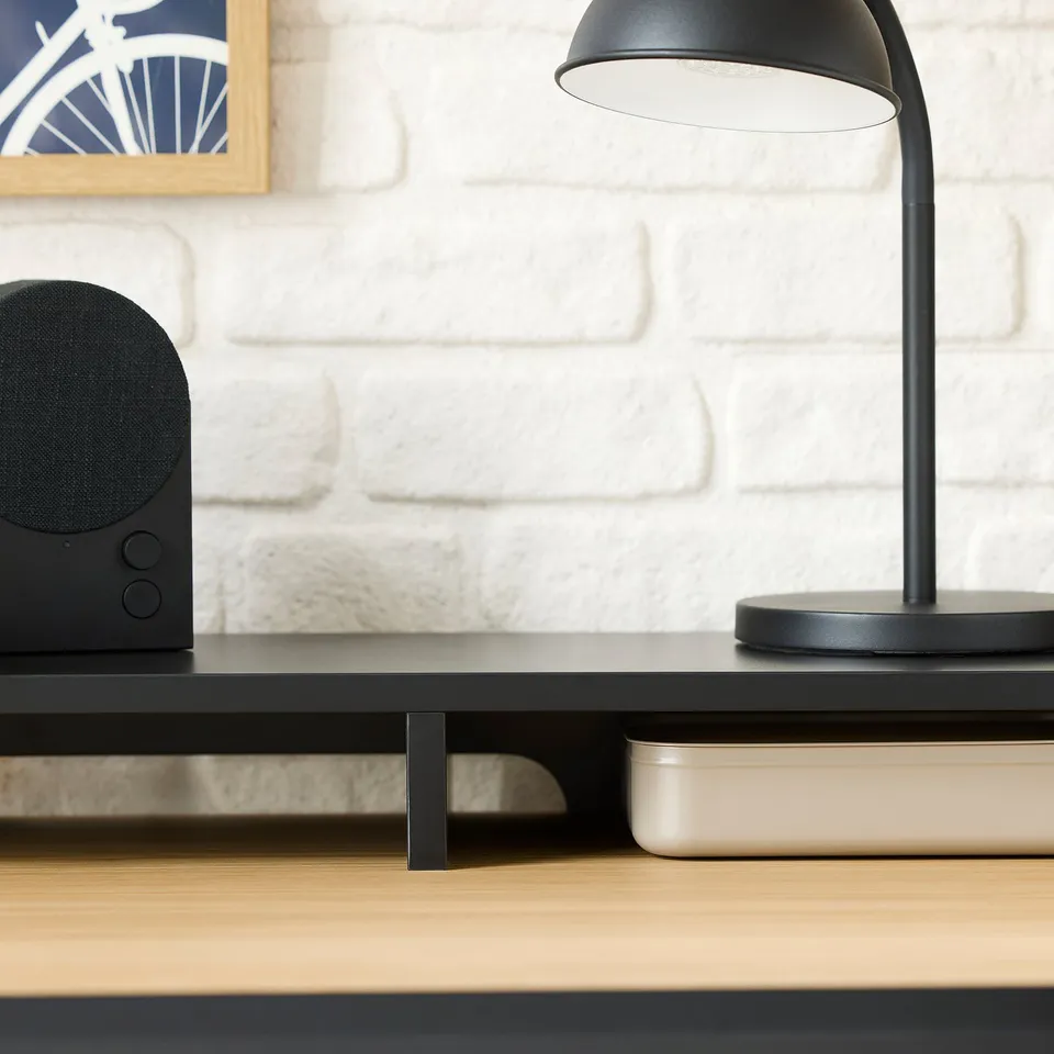 Modern desk setup with black lamp, speaker, and wireless charger.