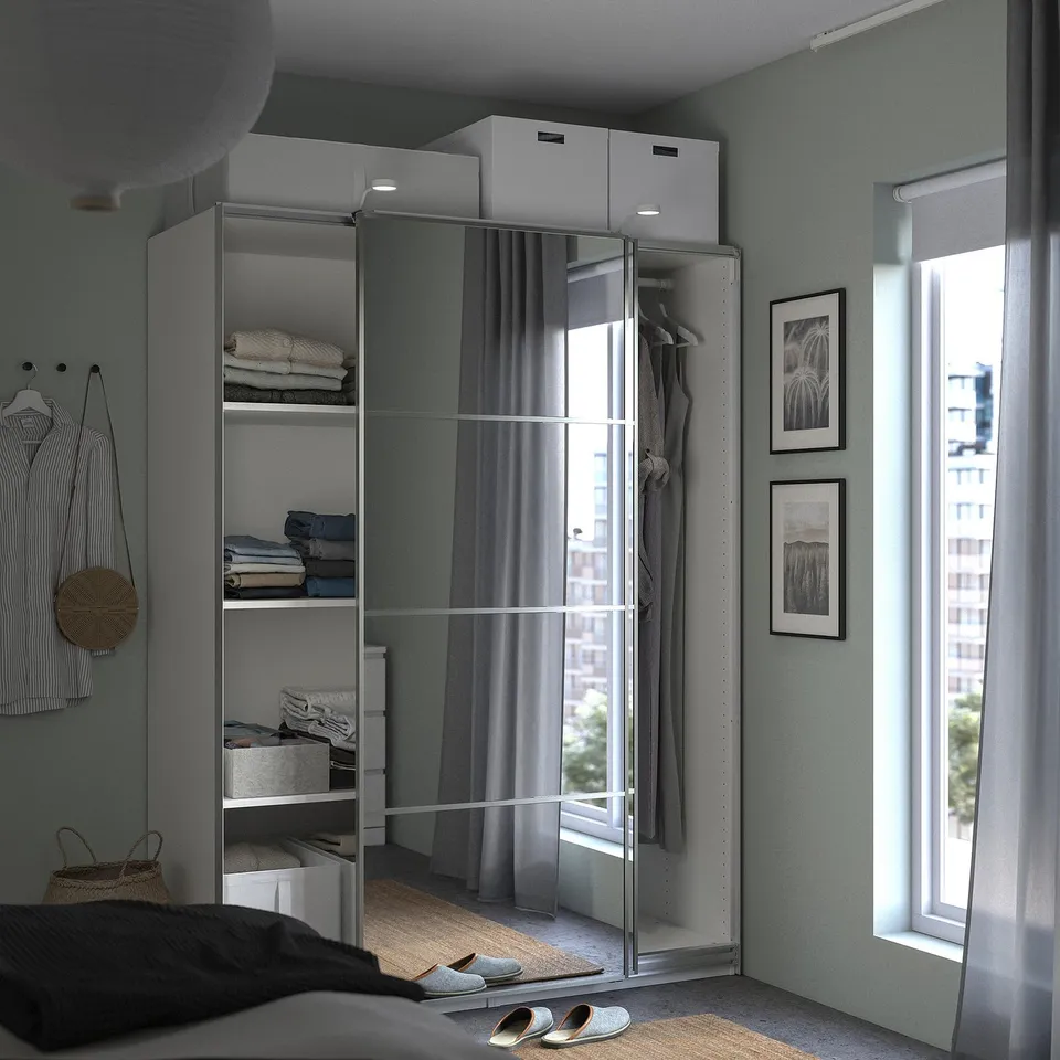 Modern bedroom with ikea PAX wardrobe, mirrored doors, and natural light.