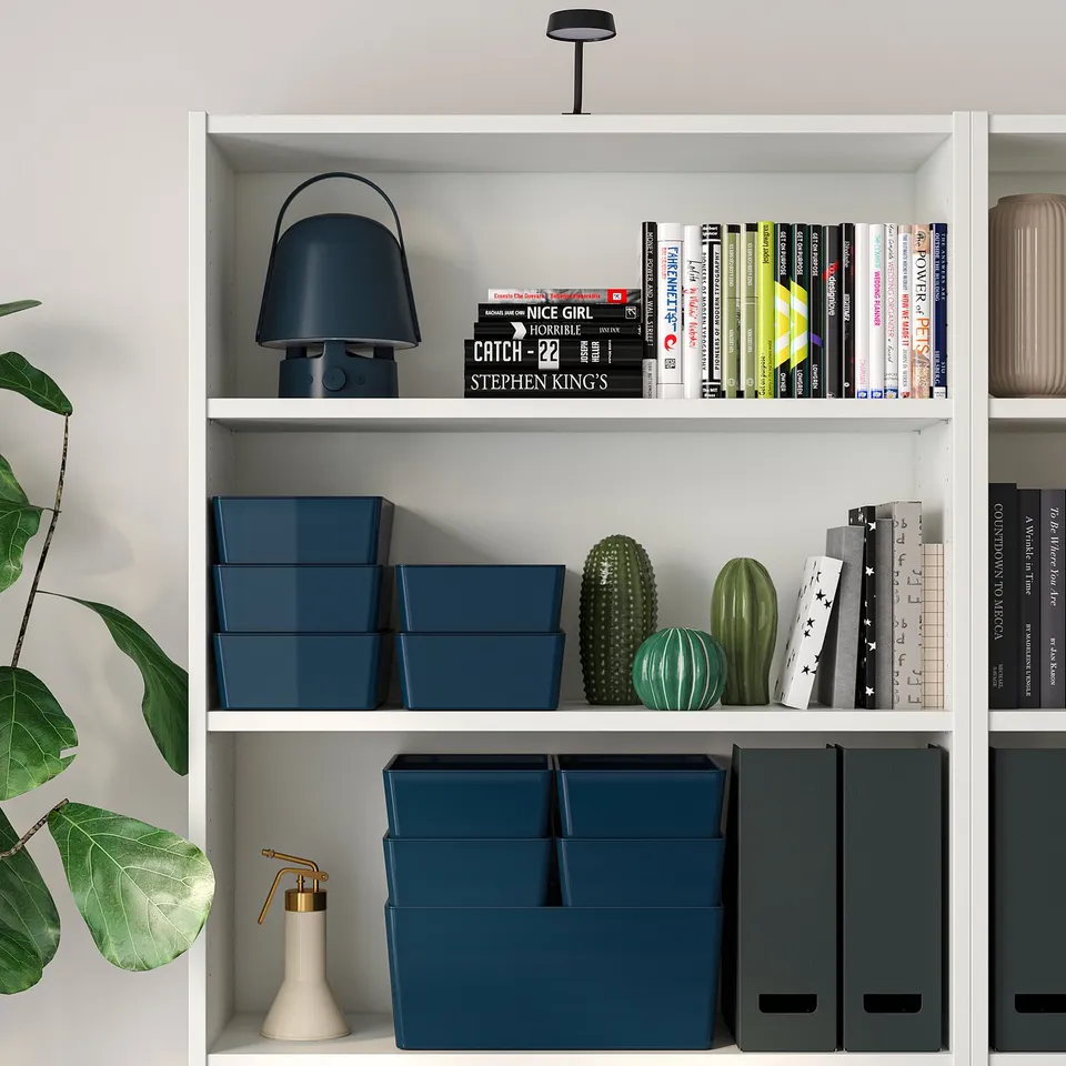 White bookshelf with blue KUGGIS boxes and decor.