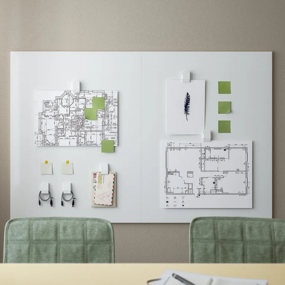 MITTZON board with blueprints, sticky notes, and markers on a wall between two green chairs for planning.