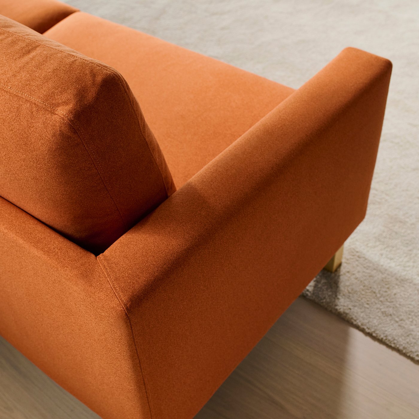 Modern sofa, burnt orange fabric, high-quality upholstery, clean lines.
