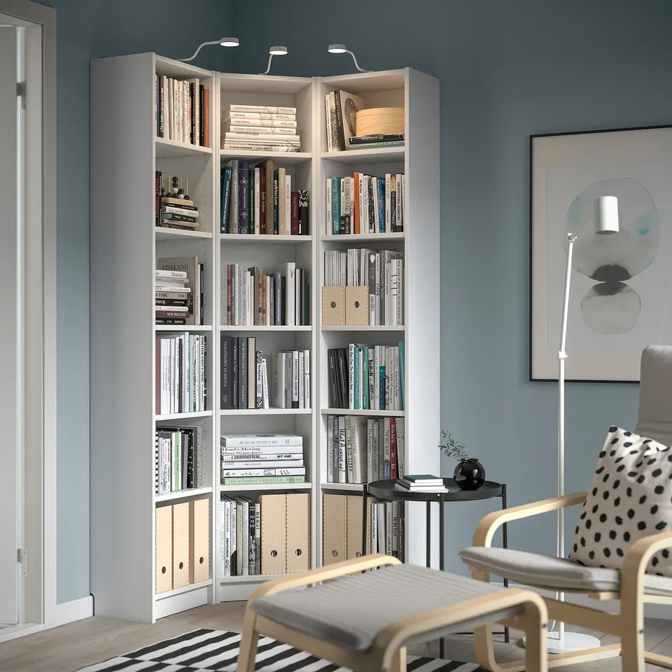 White BILLY bookcase in corner, lit, modern design.