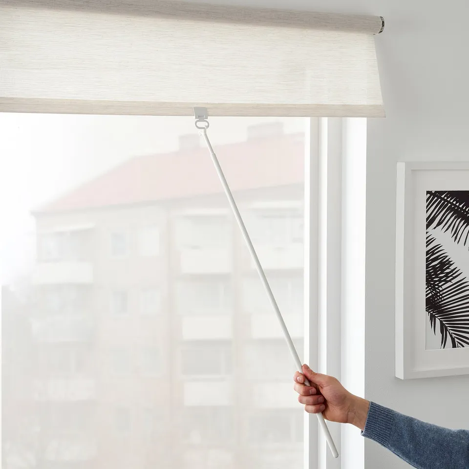 A person pulls a cordless roller blind downward, demonstrating its function to lower and philtre light for privacy.