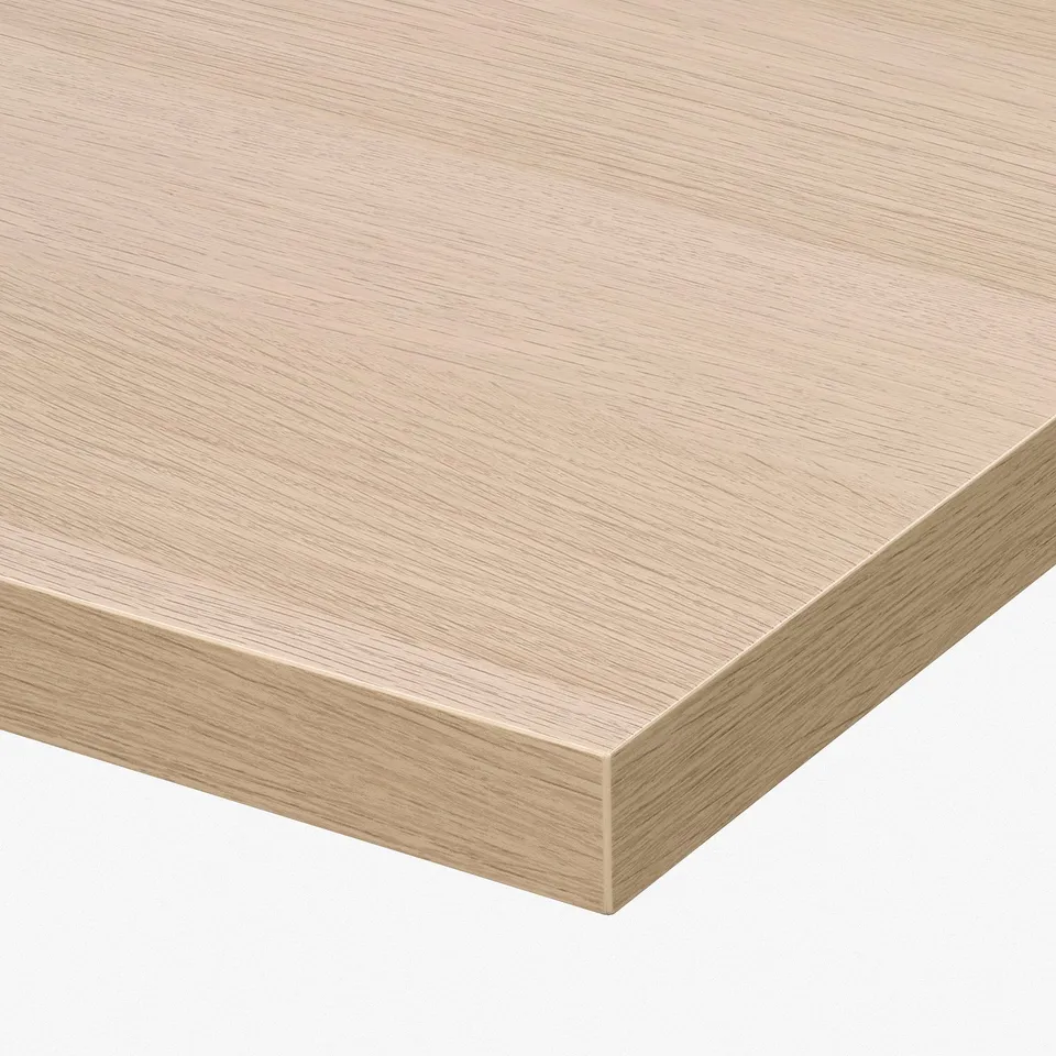 Smooth, light-colored wooden tabletop with sleek edges and fine grain texture, likely part of a modern desk setup.