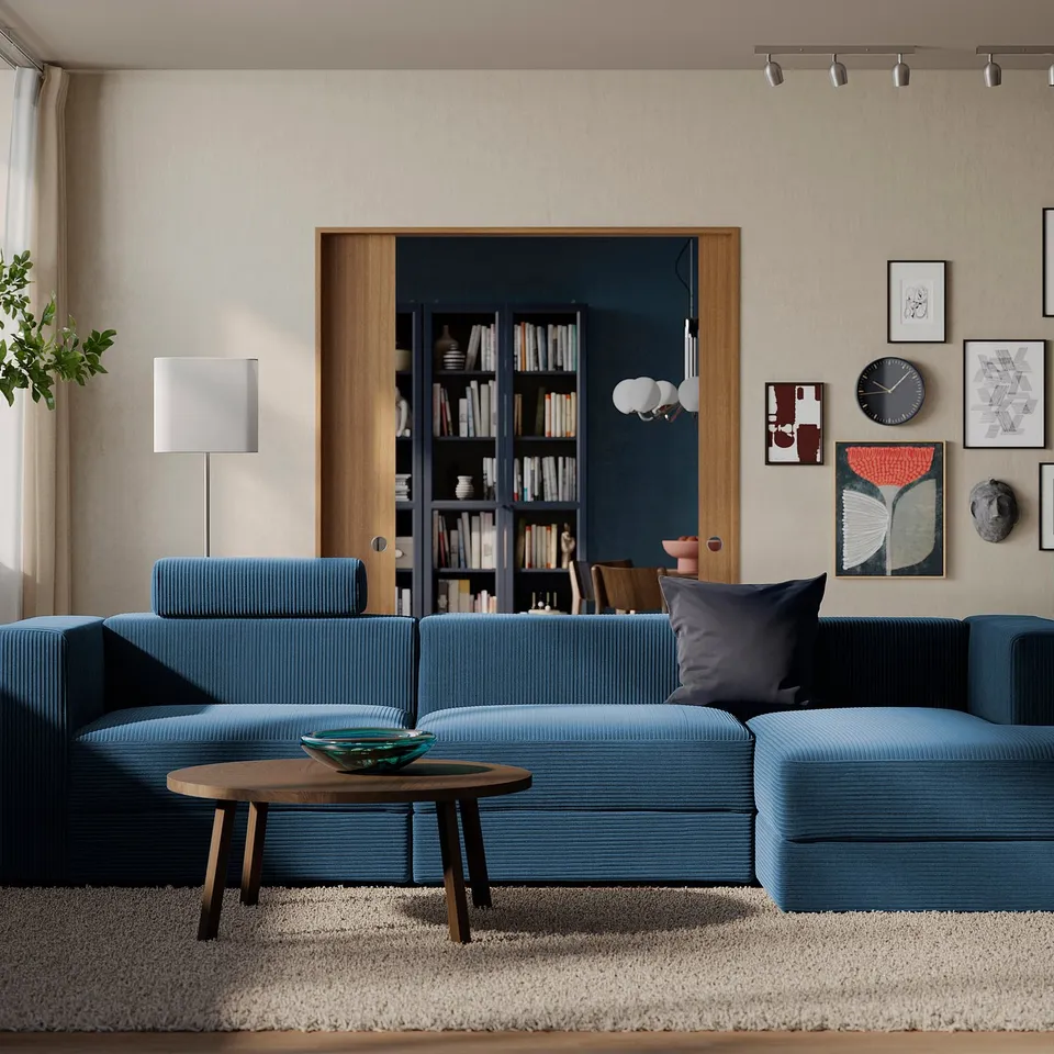 Modern living room with blue JÄTTEBO sofa, cushions, wooden table, and art wall.