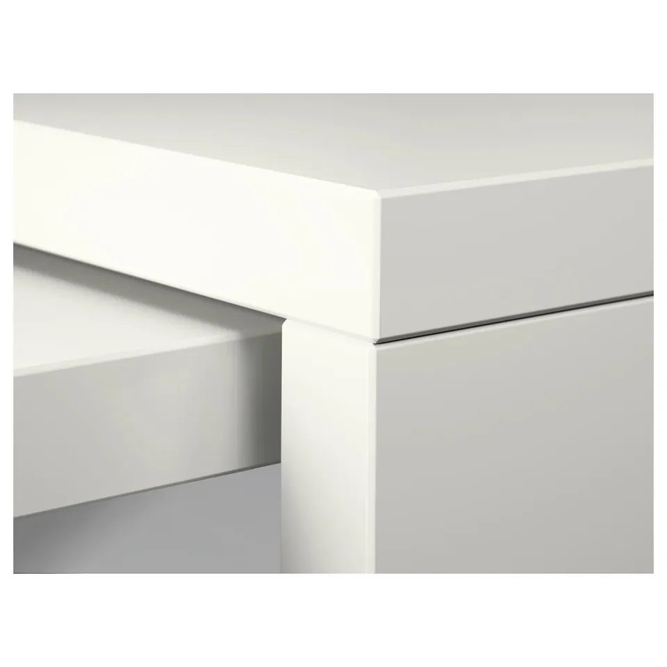 Clean, modern desk edge with smooth, white surface and sleek, hidden compartment detail.
