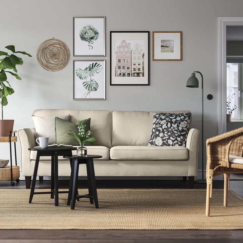 Cosy living room with beige EKHOLMA sofa, art gallery, coffee table, and wicker chair.