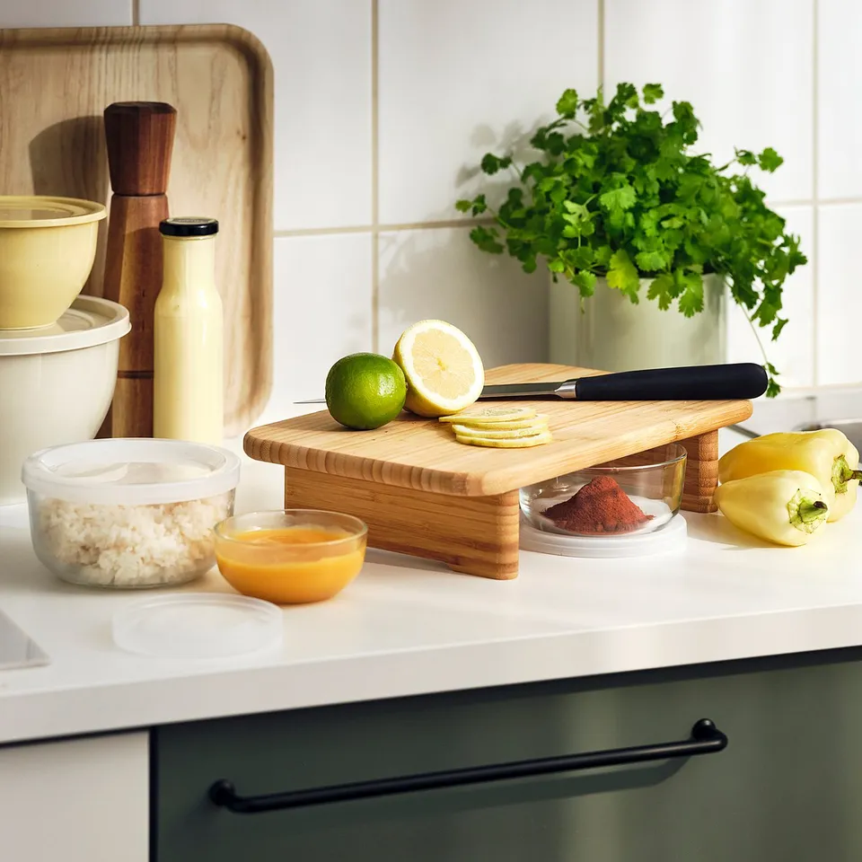 Kitchen counter with a bamboo cutting board holding lime, lemon, knife, bowls of grains, honey, and spices.