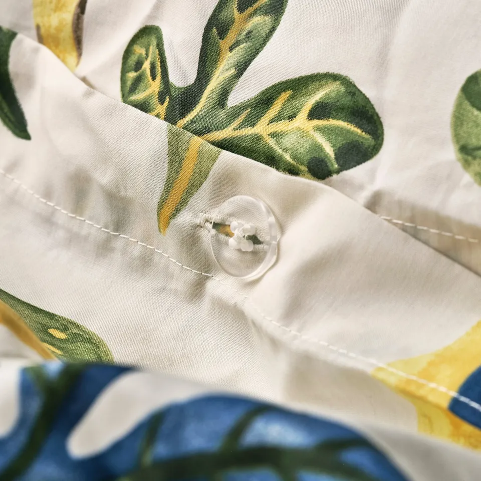 Close-up of a duvet cover with leafy pattern, showing button closure for functional detail.
